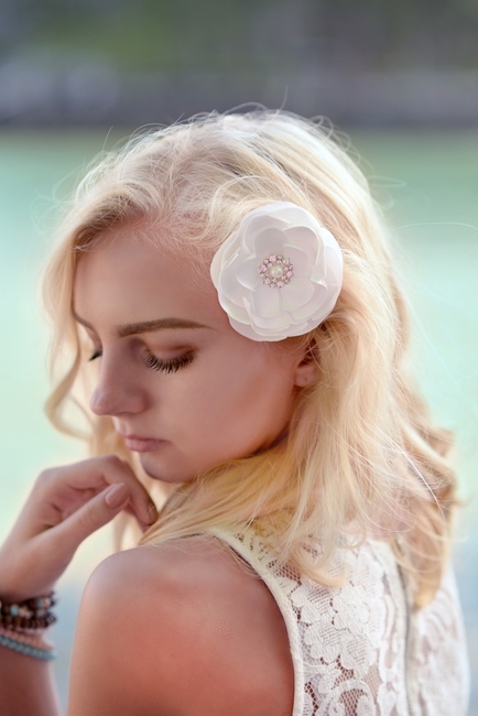 Female sitting against an old wood fence wearing a champagne chiffon hair flower